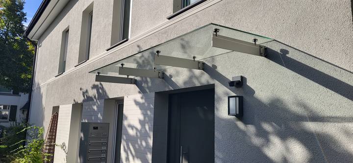 Glasvordach mit Stahlschwertern über einem Hauseingang